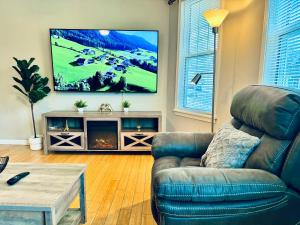 a living room with a couch and a tv on the wall at Bright, Stylish & Cozy 2Bed Unit w/Backyard & Grill Close to NYC! in Haledon