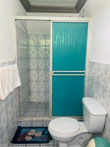 baño con aseo y puerta de ducha azul en Hostal Clary, en León