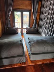 2 camas en una habitación con 2 ventanas en Hlup Homestay en Ha Giang