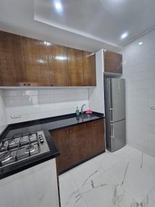 cocina con armarios de madera y nevera de acero inoxidable en Appartement moderne près de la corniche, en Nador
