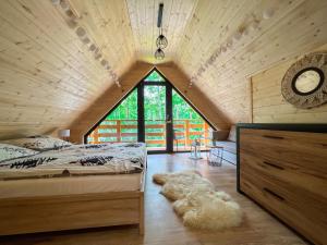 a attic bedroom with a bed and a large window at Las Lorien - wynajem domków letniskowych in Roczyny