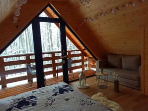 een kamer met een bed en een bank in een hut bij Las Lorien - wynajem domków letniskowych in Roczyny