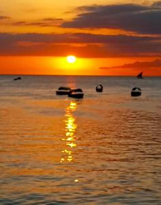 um pôr do sol sobre o oceano com barcos na água em Al Johari Hotel & Spa em Zanzibar