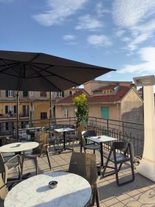 een patio met tafels en stoelen en een parasol bij PRIMA FILA in Sanremo