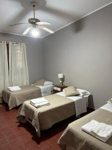 um quarto com 3 camas e uma ventoinha de tecto em La Posta del Jesuita em Villa Los Aromos