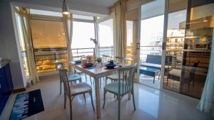 ein Esszimmer mit einem Tisch und Stühlen sowie einem Balkon in der Unterkunft Mellieha Bay 3 Bedroom Apartment ''Coastal Comfort'' in Mellieħa