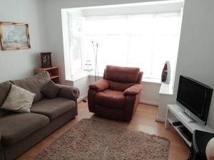 1 Bed Bognor Apartment 300 yrds from beach في بوغنور ريجيس: غرفة معيشة فيها كنب وكرسي وتلفزيون