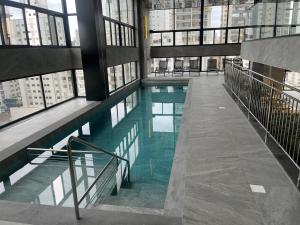 a swimming pool in a building with windows at Hotel das Américas in Balneário Camboriú