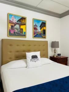 a bedroom with a white bed with two pictures on the wall at Hostal Clary in León