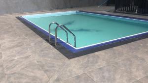 a large swimming pool with blue water and metal steps at Grand Winterberry - Lake View Luxury Residence in Nuwara Eliya
