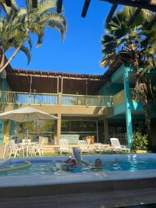 a woman laying in the swimming pool at a resort at Pousada da Tina in Anchieta