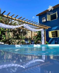 una piscina con pérgola y una casa en Pousada da Tina, en Anchieta