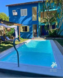 a swimming pool in front of a blue house at Pousada da Tina in Anchieta