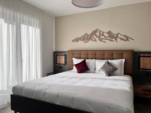 a bedroom with a large bed with mountains on the wall at Hotel Rododendro Val di Fassa in Campitello di Fassa