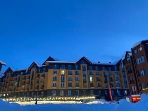 un gran edificio en la nieve por la noche en Brand new apartment near Gondola, en Gudauri
