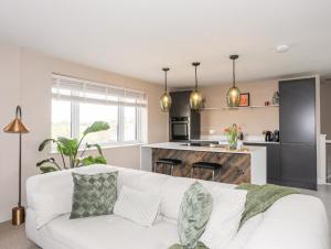 a living room with a white couch and a kitchen at The Hayloft in Amlwch