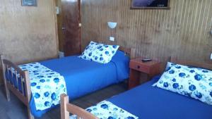 2 camas en una habitación con sábanas y almohadas azules en Hostal El Colibri, en Vicuña