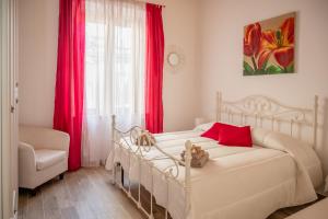 a bedroom with a white bed with red pillows and a window at La Casa nel Vicolo in Colle di Val d'Elsa