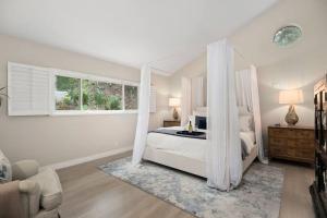 Dormitorio blanco con cama con dosel y ventana en Asian Oasis Stunning Canyon Views - Luxury Home, en Glendale