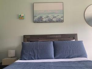 a bed with blue pillows and a picture on the wall at Walk to the beach, Studio, with Pool and FREE Parking in Hallandale Beach