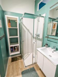 La salle de bains est pourvue d'une douche et d'un lavabo. dans l'établissement Le Cocon Bleu - Appartement Calme - Parking Gratuit - Fibre, à Arras