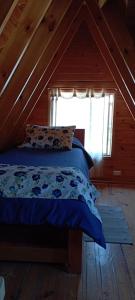 a bed with a blue comforter in a room with a window at Hostal El Colibri in Vicuña