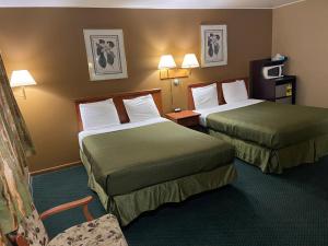 a hotel room with two beds and a chair at Colonial Inn in Dyersville