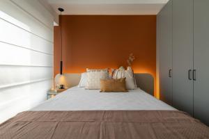 a bedroom with a large bed with an orange wall at Studio Alto Padrão Brooklin in Sao Paulo