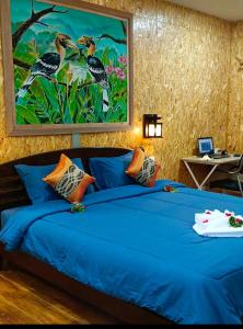 ein Schlafzimmer mit einem blauen Bett und einem Gemälde an der Wand in der Unterkunft Easy Life Country House in Ko Lanta