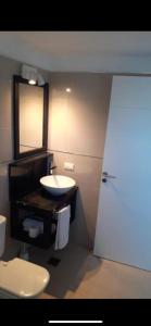 un bagno con lavandino, WC e specchio di Linda Bay Resort y Spa Monoambiente a Mar de las Pampas