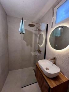 ein Bad mit einem Waschbecken und einer Dusche mit einem Spiegel in der Unterkunft Casa Poseidon in Hvar