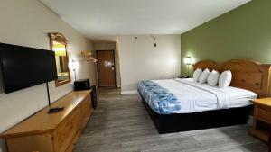 a hotel room with a bed and a flat screen tv at Regency Inn and Suites in Stilwell