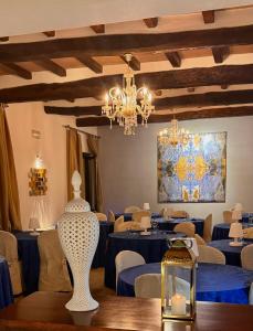 un comedor con mesas azules y una lámpara de araña en La Siègià Resort spa, en Massa Marittima