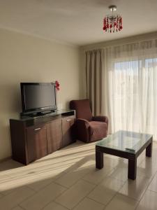 ein Wohnzimmer mit einem TV, einem Stuhl und einem Couchtisch in der Unterkunft Luxury Cozy Apartment near NISSI BEACH in Ayia Napa
