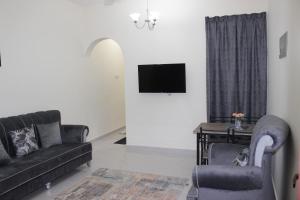 sala de estar con sofá y TV en أمجاد للشقق الفندقية, en Al Ḩuwayl