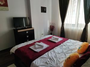 a bedroom with a bed with towels and a tv at Cozy Magic House - Unirii Square in Bucharest