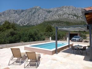 a pool with chairs and a table with a view of mountains at Relax in Orebić
