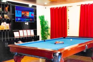 una TV e un tavolo da biliardo in una camera con tende rosse. di Villa Valencia Private Resort a Santa Rita