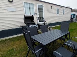 einen Picknicktisch und Stühle mit einem Grill sowie einem Tisch und Stühlen in der Unterkunft Holiday Cottage Seaside in Knokke-Heist