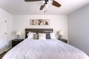um quarto com uma cama branca e uma ventoinha de tecto em Cheerful 3 bedroom house with patio em Auburn