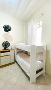 Litera blanca en habitación con ventana en Hostel Canto Zen en Salvador
