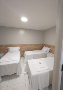 a room with two beds with white sheets and tables at Pousada Chapada do Araripe in Araripina