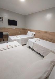 a room with three beds and a flat screen tv at Pousada Chapada do Araripe in Araripina