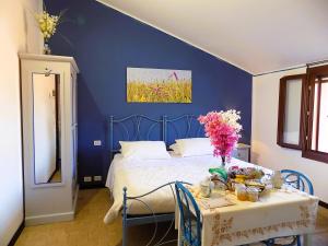 Un dormitorio azul con una cama y una mesa con flores. en Relais Cà del rio en Botteghino
