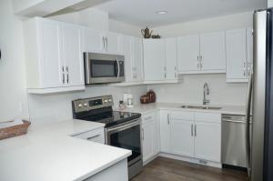 a white kitchen with white cabinets and a microwave at Cozy Haven in Winnipeg