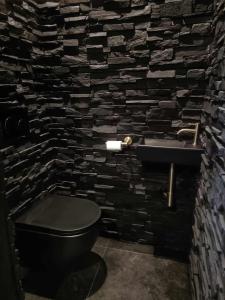 a bathroom with a black toilet and a stone wall at La Chambre Delta in Morlanwelz-Mariemont