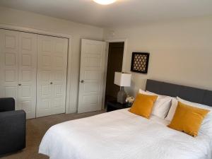 a bedroom with a bed with white sheets and orange pillows at Cozy Haven in Winnipeg