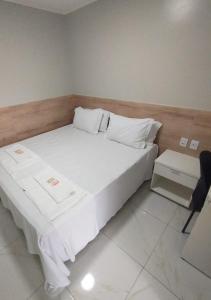 a bedroom with a large white bed and a chair at Pousada Chapada do Araripe in Araripina
