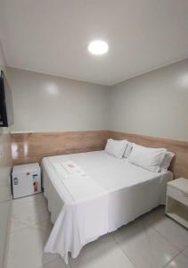 a bedroom with a white bed and a television at Pousada Chapada do Araripe in Araripina