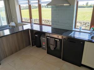 una cocina con encimera negra y ventanas en Irish Cottage Tipperary, en Carney